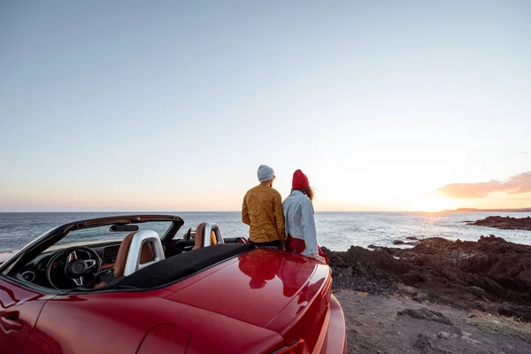 Härligt par på stranden nära bilen på en solnedgång — Stockfoto