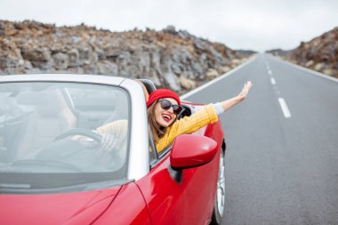 Cabriolet arabasıyla volkanik vadide seyahat eden bir kadın.