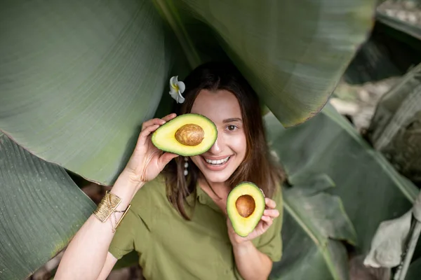 Woman with avocado in banana leaves — Stock Photo, Image