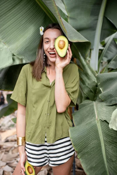 Woman with avocado in banana leaves — Stockfoto