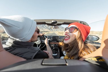 Bir çift seyahat ederken araba kullanıyor.