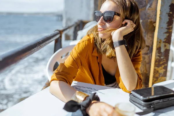 Расслабленная женщина на террасе у океана — стоковое фото