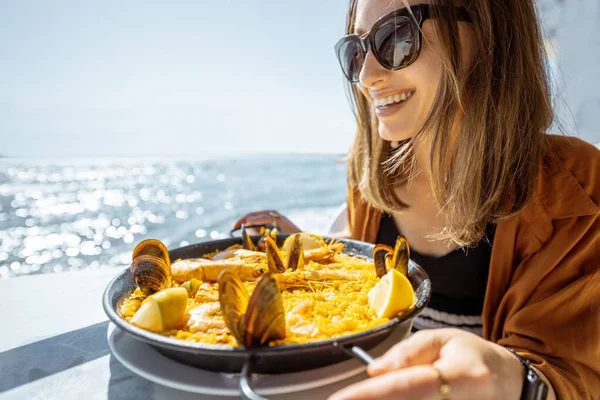 Okyanus kenarında deniz ürünleri yiyen bir kadın. — Stok fotoğraf
