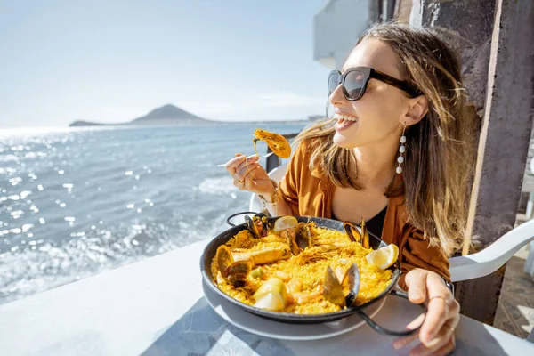 Mulher comendo comida do mar perto do oceano — Fotografia de Stock