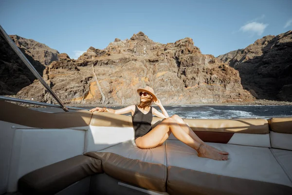 Mujer relajada navegando en el yate cerca de la costa rocosa — Foto de Stock