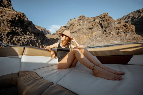 岩の多い海岸近くのヨットに乗っているリラックスした女性 — ストック写真