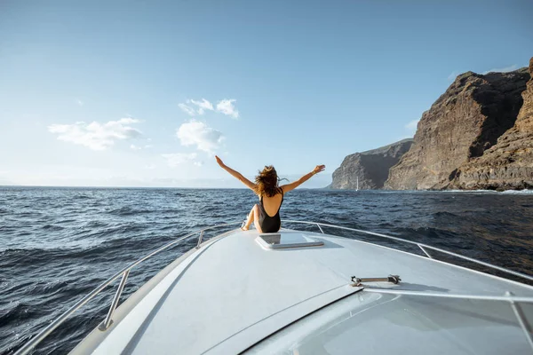 Mujer navegando en el yate cerca de la costa rocosa — Foto de Stock