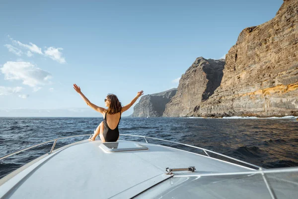 Mujer navegando en el yate cerca de la costa rocosa — Foto de Stock