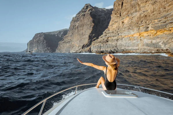 Mujer navegando en el yate cerca de la costa rocosa — Foto de Stock