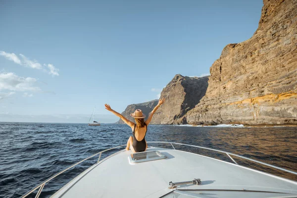 Mujer navegando en el yate cerca de la costa rocosa — Foto de Stock