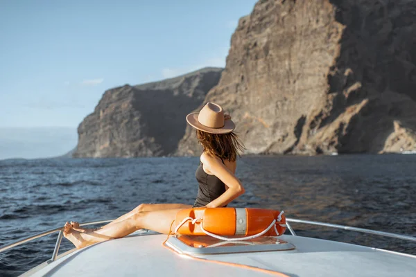Kayalık sahilin yakınındaki yatta yelken açan bir kadın. — Stok fotoğraf
