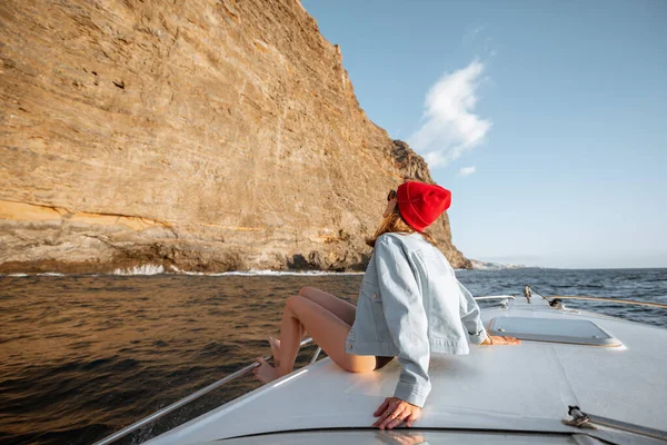 Kayalık sahilin yakınındaki yatta yelken açan bir kadın. — Stok fotoğraf