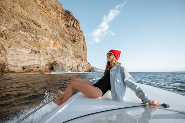 在岩石海岸附近的游艇上航行的女人 — 图库照片