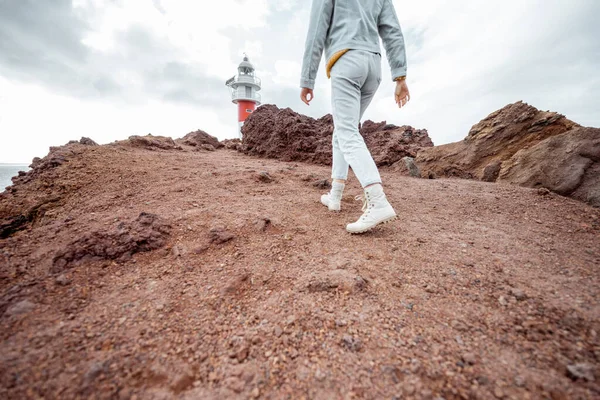 Cestovatel kráčí po skalnaté krajině v blízkosti majáku — Stock fotografie