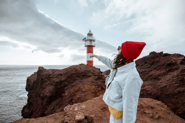 Женщина путешествует по скалистым ландшафтам возле маяка — стоковое фото