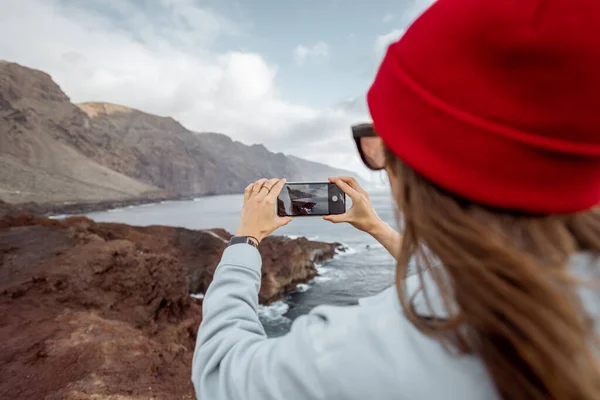 Žena fotografování úchvatný výhled na skalnaté pobřeží — Stock fotografie