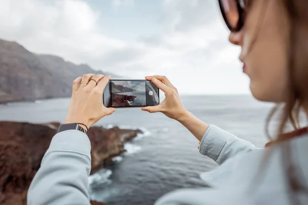 Mujer fotografiando impresionantes vistas de la costa rocosa —  Fotos de Stock
