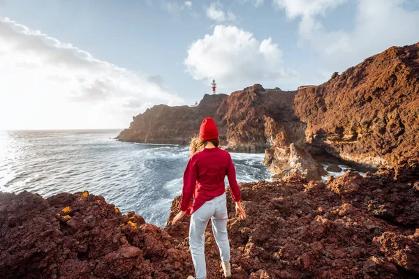 Vrouw op de rotsachtige oceaan bij de vuurtoren — Stockfoto