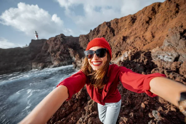 Žena cestující na skalnatém pobřeží oceánu v blízkosti majáku — Stock fotografie