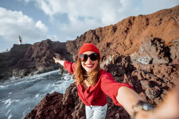 Женщина, путешествующая по скалистому океану возле маяка — стоковое фото