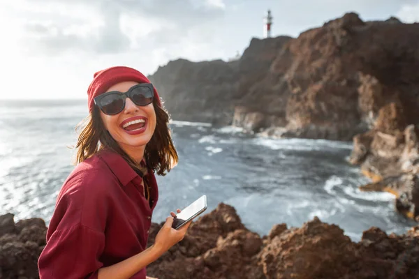 Mujer viajando en la costa rocosa del océano cerca del faro —  Fotos de Stock