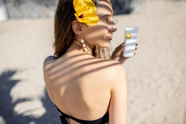 Літня дівчина з сонцезахисним лосьйоном на пляжі — стокове фото