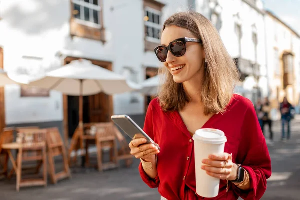 Vrouw met koffie en telefoon in de oude stad — Stockfoto
