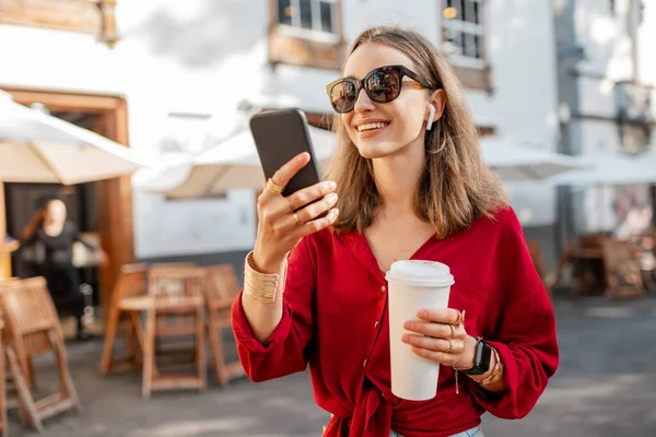 旧市街にコーヒーと電話を持つ女性 — ストック写真