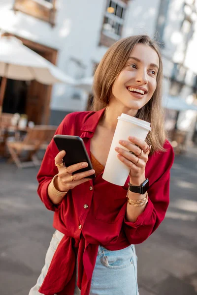 旧市街にコーヒーと電話を持つ女性 — ストック写真