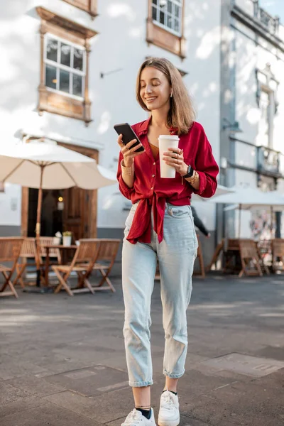 旧市街にコーヒーと電話を持つ女性 — ストック写真