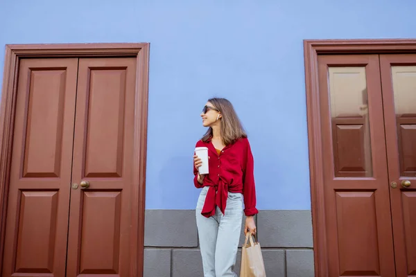 Стильная женщина с кофе на фоне цветной стены — стоковое фото