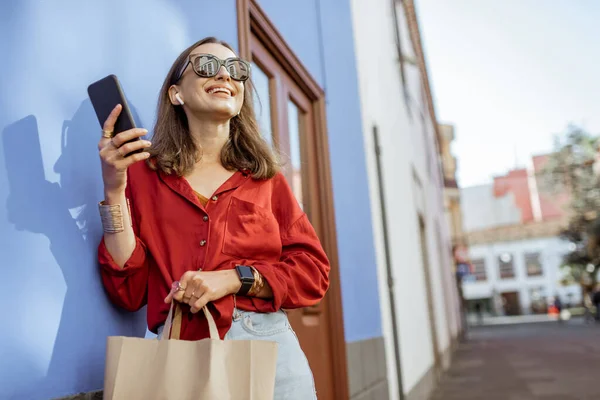 Stijlvolle vrouw met mobiele telefoon op de kleur muur achtergrond — Stockfoto