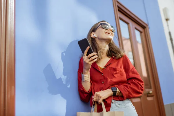 Snygg kvinna med mobiltelefon på färg vägg bakgrund — Stockfoto