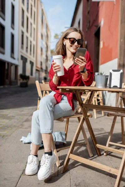Женщина с телефоном и кофе на террасе кафе на открытом воздухе — стоковое фото