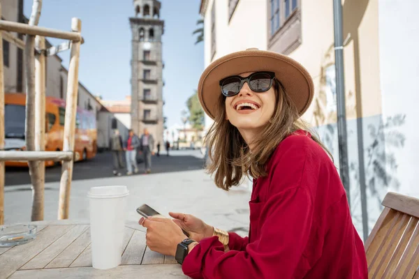 Onnellinen nainen lepää kahvilan terassilla vanhassa kaupungissa — kuvapankkivalokuva