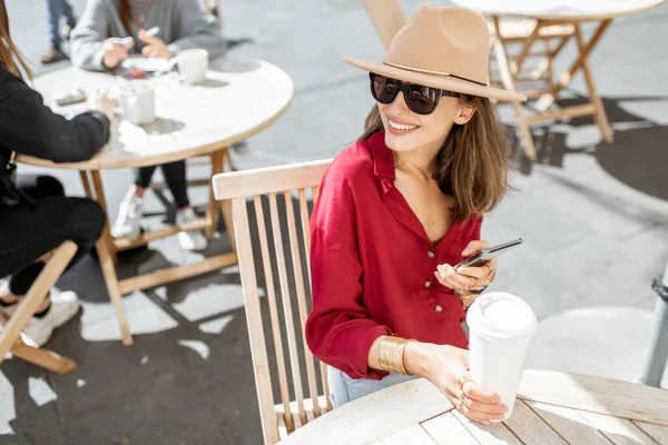 Kvinna med mobiltelefon och kaffe på caféets terrass — Stockfoto