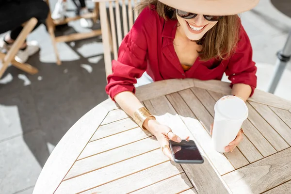 Женщина с мобильным телефоном и кофе на террасе кафе — стоковое фото