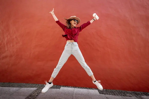 Portrait of a stylish woman with coffee cup on the red wall background — Stock Photo, Image