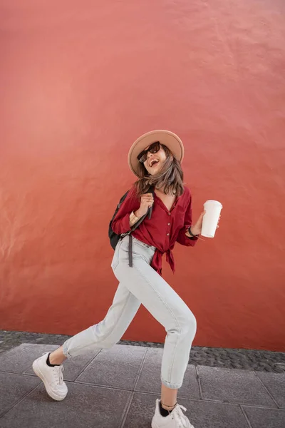 Retrato de una mujer con estilo con taza de café en el fondo de la pared roja —  Fotos de Stock