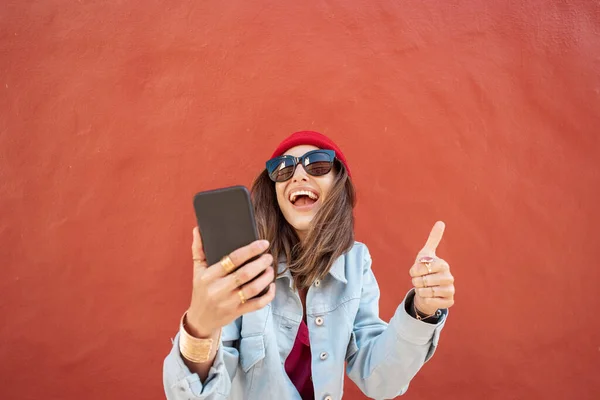 Женщина с телефоном на красном фоне на улице — стоковое фото