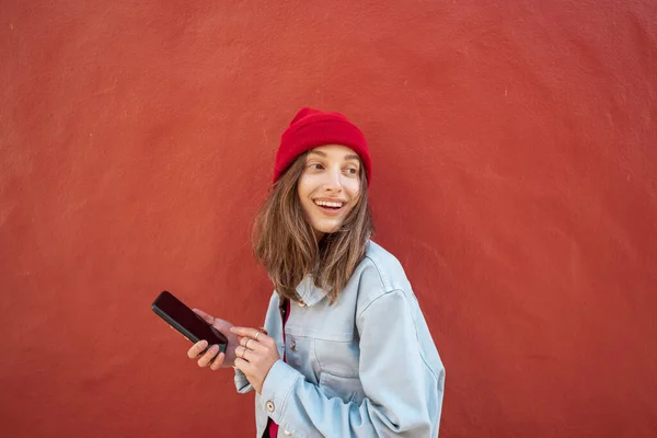 Mujer con teléfono en el fondo rojo al aire libre —  Fotos de Stock