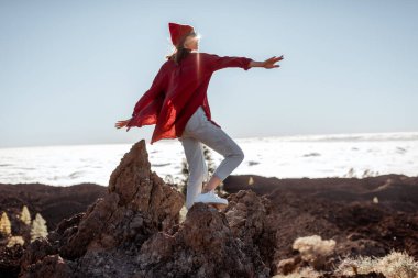 Bulutların üstündeki kayalık arazide bir kadın