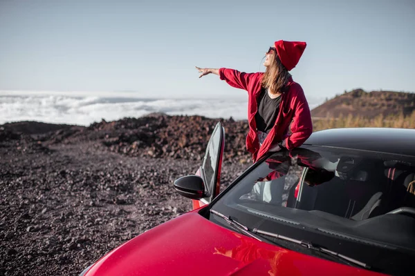 在云彩之上的岩石地形上开车旅行的女人 — 图库照片
