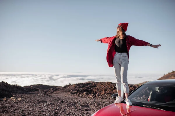 Mulher viajando de carro no terreno rochoso acima das nuvens — Fotografia de Stock