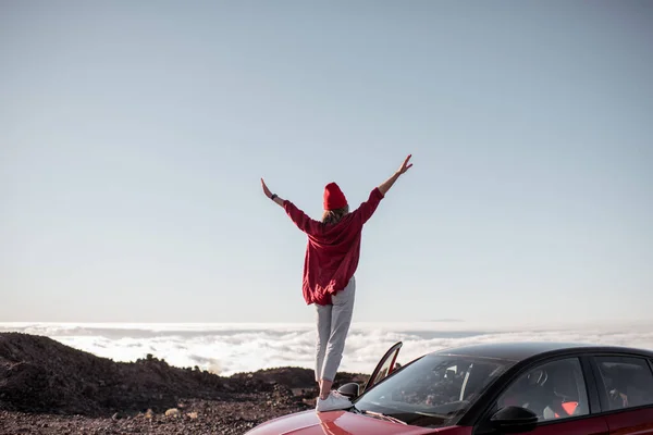 Žena cestující autem po skalnatém terénu nad mraky — Stock fotografie