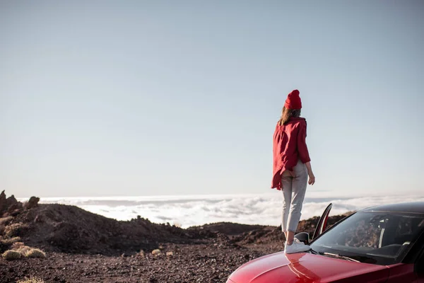 Frau mit Auto im felsigen Gelände über den Wolken unterwegs — Stockfoto
