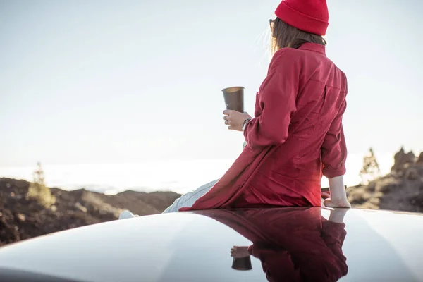 Woan mit Kaffee auf dem Autodach über den Wolken — Stockfoto