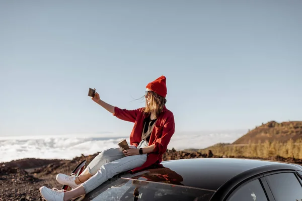 Woman traveling by car on the rocky terrain above the clouds — Stock Photo, Image