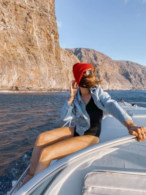 Woman sailing on a yacht near rocky shore