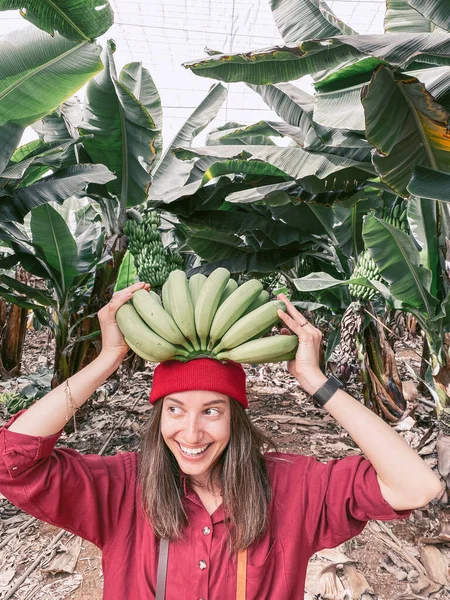 Woman with a stem of fresh green bananas on the plantation — Zdjęcie stockowe